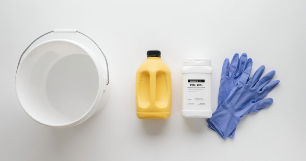 Muriatic acid jug and sodium bisulfate dry acid container beside a 5-gallon bucket