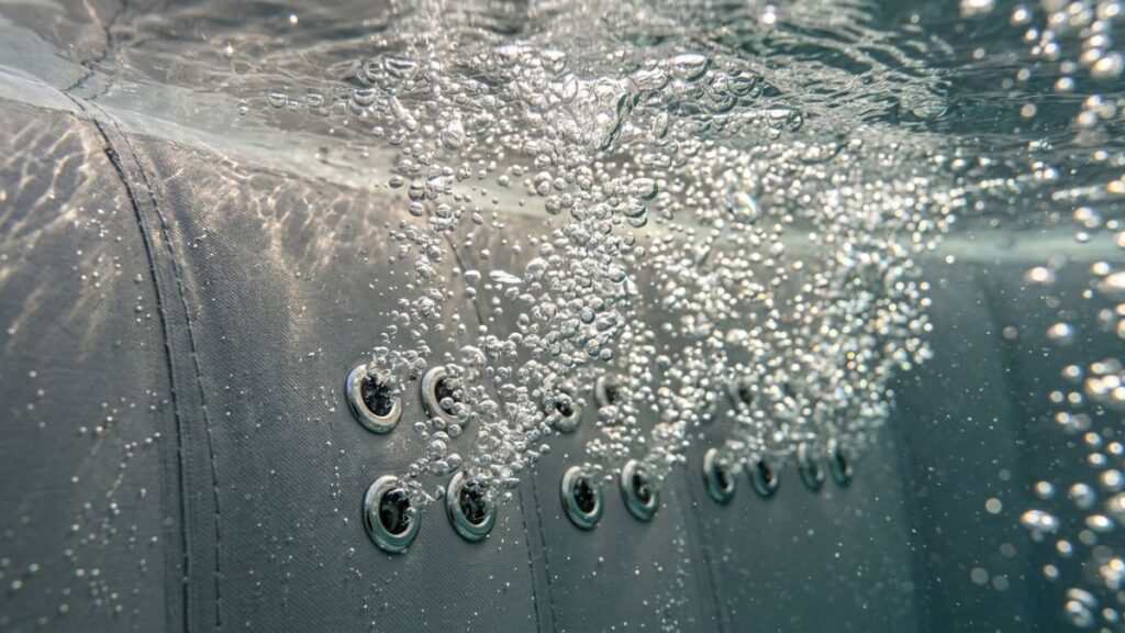 Close-up of inflatable hot tub air jet holes blasting CO2 bubbles through water causing pH to rise constantly