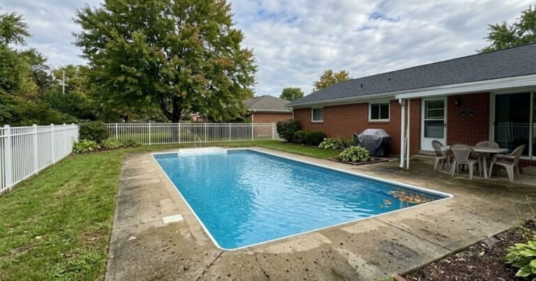 Real American backyard swimming pool before phosphate treatment with a few leaves floating on clear water