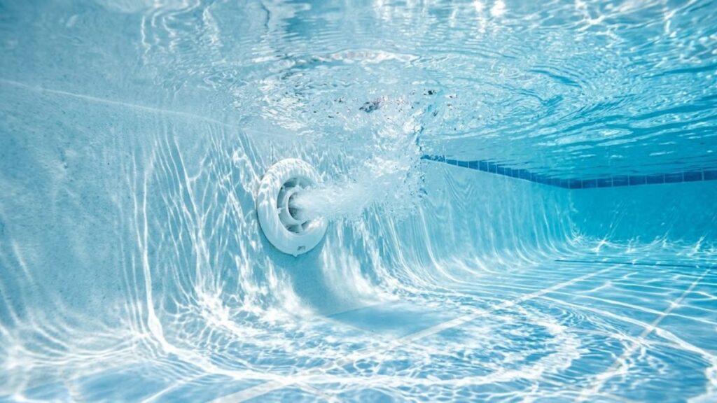 Swimming pool return jets circulating water for even chemical distribution.